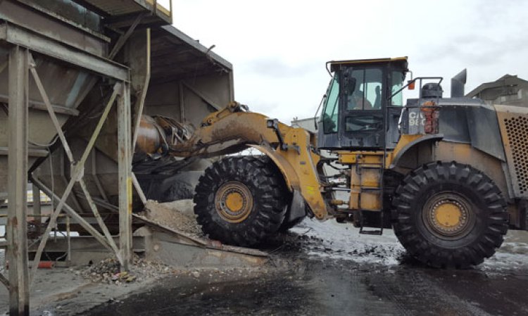 Case study of a cement plant using front end-loaders to unload barges of rock gypsum into a pyramid hopper.